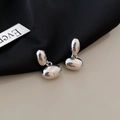 Detailansicht silberner minimalistischer Doppelbohnen-Ohrringe auf edlem Stoff - Unregelmäßiger Bohnen-Drop-Stil / Silber