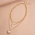 Dettaglio della collana tripla dorata con ciondoli a cuore e perle sintetiche - Oro
