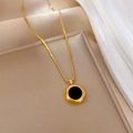Macro-detailopname van de gouden schakelketting en ronde zwarte schelphanger - Goud