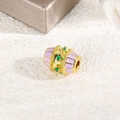 Dettaglio macro di una perla a barilotto dorata con smalto lavanda e zircone smeraldo - Viola Chiaro