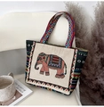 Ethnic canvas tote bag with elephant embroidery and colorful geometric straps on a chair - Orange Elephant