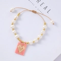 Detail of adjustable pearl bracelet with pink heart charm and gold bead accents - Pink Background Gold Heart