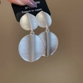 Vista macro di orecchini pendenti argento con trama in metallo spazzolato e design a foglia - Argento