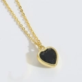 Macro view of a delicate golden chain with a black heart-shaped gemstone pendant - Black