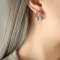 Orecchini minimalisti a doppia C in finitura argento indossati da una modella - Argento