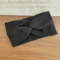 Solid black ribbed knit headband with twist knot design on a wooden surface - Ribbed Style / Black