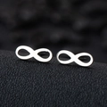 Polished silver infinity stud earrings in stainless steel on black leather background - Infinity / Silver