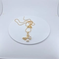 Detail of a gold butterfly pendant with micro-pave cubic zirconia on a white pedestal - Pendant Necklace / White Butterfly