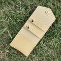 Detail view of beige leather jewelry pouch with snap button and straps on grass - 13.3*6cm / Leather Apricot