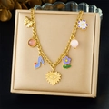Gouden NK-schakelketting met bedeltjes van bloemen en strikken op een beige sieradendoosje - Gouden Multi-Charm Stijl (N3751)