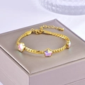 Detailed shot of golden snake chain bracelet with opal-style floral charms on jewelry box - Bracelet