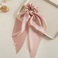 Nahaufnahme von rosa Satin-Haargummi mit langen Bändern auf Holzdeko-Display - Rosa