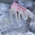 Detailed view of a white wavy hair claw clip on soft tissue paper background - Jelly White