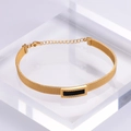 Dettaglio di un bracciale in maglia di titanio dorato con rettangolo nero e greca - Oro