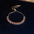 Macro view of adjustable gold-plated bracelet with radiant pink baguette zircons - Purple Oval Style / Gold