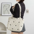 Detail of quilted tote bag featuring black bow embroidery and elegant cream fabric - Beige Fabric with Embroidered Bow