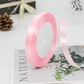 Pink 1cm satin ribbon roll for gift wrapping and DIY crafts on a natural background - Pink