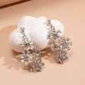 Macro view of crystal flower earrings with sparkling silver finish on a cloud stand - Earrings-Silver/Clear Rhinestone