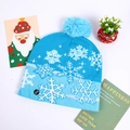 Detail of blue knitted Christmas hat with LED power switch and white snowflake patterns - Blue With White Snowflakes