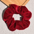 Macro-opname van de wijnrode fluwelen scrunchie met zachte textuur en vintage glans op steen - Rood