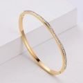 Bracciale rigido in titanio dorato con zirconi brillanti su un supporto geometrico - Oro