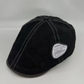 Close-up of black retro beret with white contrast stitching and side woven label - M / Black