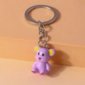 Close-up of a purple resin bear keychain with silver metal ring on a textured surface - Purple