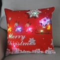 Detail of LED Christmas pillow showing glowing lights and Santa Claus on a beige sofa - Red Base Santa City Silhouette-21M-19