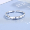 Minimalist silver wavy ring with blue zircon gemstone on light blue background - Adjustable Open / White Gold