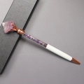 Detail of rose gold ballpoint pen featuring pink crystal top and purple stone filling - Amethyst