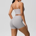 Detail of light gray yoga set featuring thin straps and high-waisted shorts on a model - Frost Grey