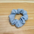 Light blue pleated fabric scrunchie hair tie on a natural wooden background - Small / Blue