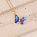 Vue macro du pendentif papillon avec cristal dégradé violet-bleu et chaîne dorée fine - Violet foncé