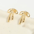 Detailed view of golden bow earrings with a central clear zircon stone on a minimal base - Gold - Large