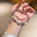 Detailed view of layered amethyst and pearl bead bracelet with zircon charm on woman's wrist - Natural Amethyst Freshwater Pearl Zircon Ball Style