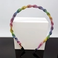 Detailed shot of rainbow rhinestone twisted headband on a white display block - Colorful Zirconia
