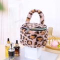 Close-up detail of plush leopard print cylindrical makeup bag with rainbow zipper - Pink
