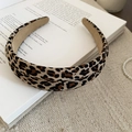 Close-up of leopard print fabric headband placed on an open book with knit background - Headband Style (Headband-Coffee) / Coffee Leopard