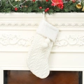 Calza di Natale bianca in maglia con pompon appesa su una decorazione festiva del camino - Bianco