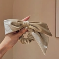 Detail of a beige velvet hair scrunchie with large bow and gold charm accessory - Champagne