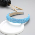 Macro detail of blue glitter wide headband with textured sparkle finish on white base - Blue