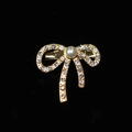 Dettaglio della spilla a fiocco dorata con strass incastonati e grande perla centrale - Oro