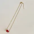 Detail view of gold adjustable box chain with a red bean pendant on white background - Universal Chain / Red