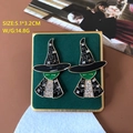 Dettaglio orecchini a forma di strega con smalto nero e gemme verdi su velluto verde - 626 Strega di Halloween
