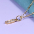 Close-up of golden necklace with a rectangular clear gemstone pendant on fine chain - Alexandrite Champagne (June) - Gold