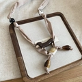 Dettaglio del cordino per telefono con ciondolo bassotto in tessuto beige e ambra - Beige (Pendente Bassotto)