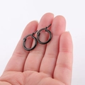 Nahaufnahme von matt-schwarzen Huggie-Creolen aus Edelstahl in der Hand gehalten - Schwarz 20 X 10 Mm / Schnelle Lieferung