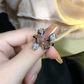 Silver wavy geometric ring featuring three clear round gemstones on a model's finger - No. 15 Open Ring