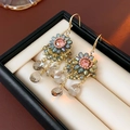 Détail de boucles d'oreilles fleuries perlées avec cristaux en goutte sur écrin - Style Crochet Or-Bleu