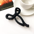 Matte black bow hair claw clip on a minimalist white table with a coffee cup and card - Matte Black